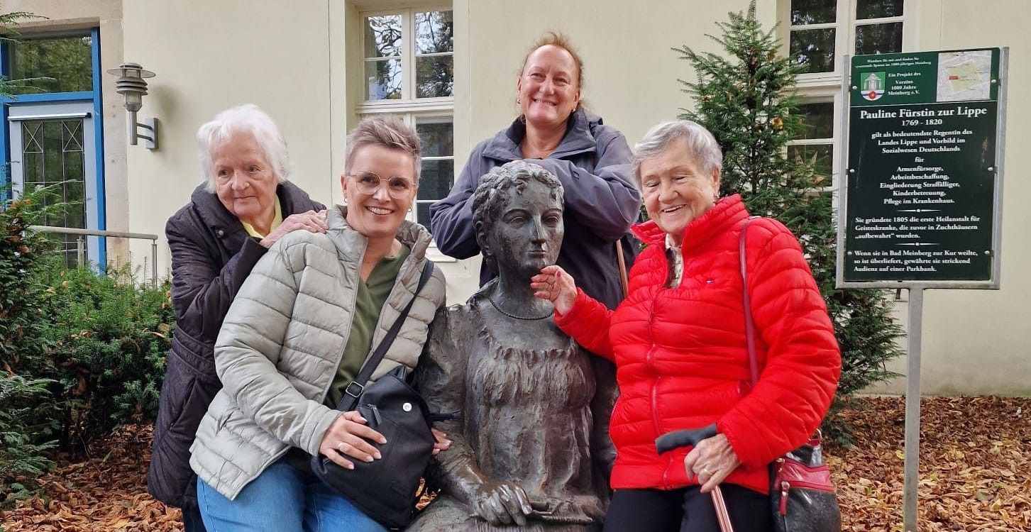 A group of women are posing for a picture with a statue of a woman.