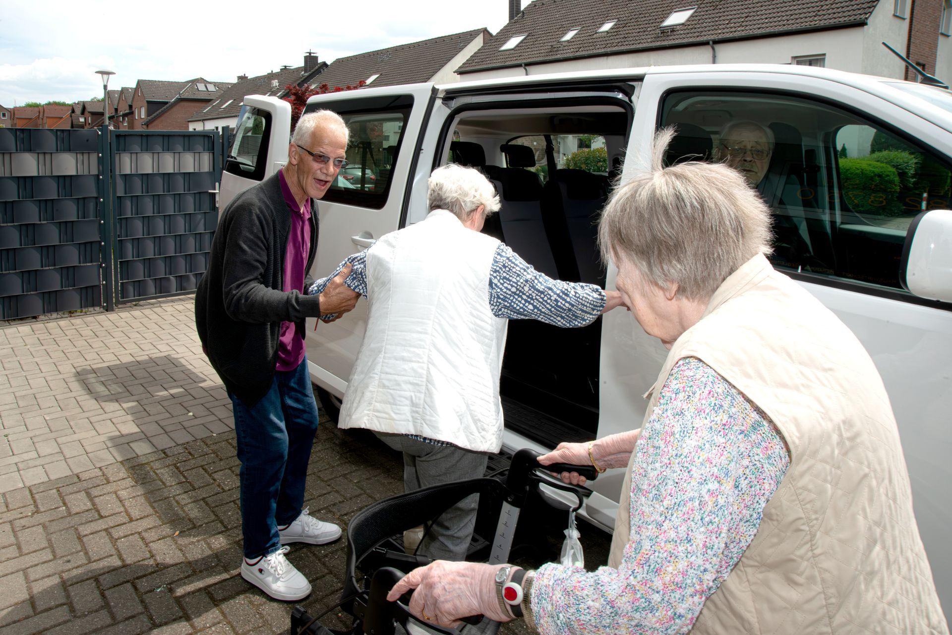 Mann hilft alter Frau in den Wagen