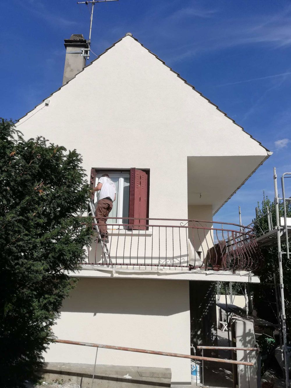 Façade rénovée d'une maison avec un professionnel sur une échelle