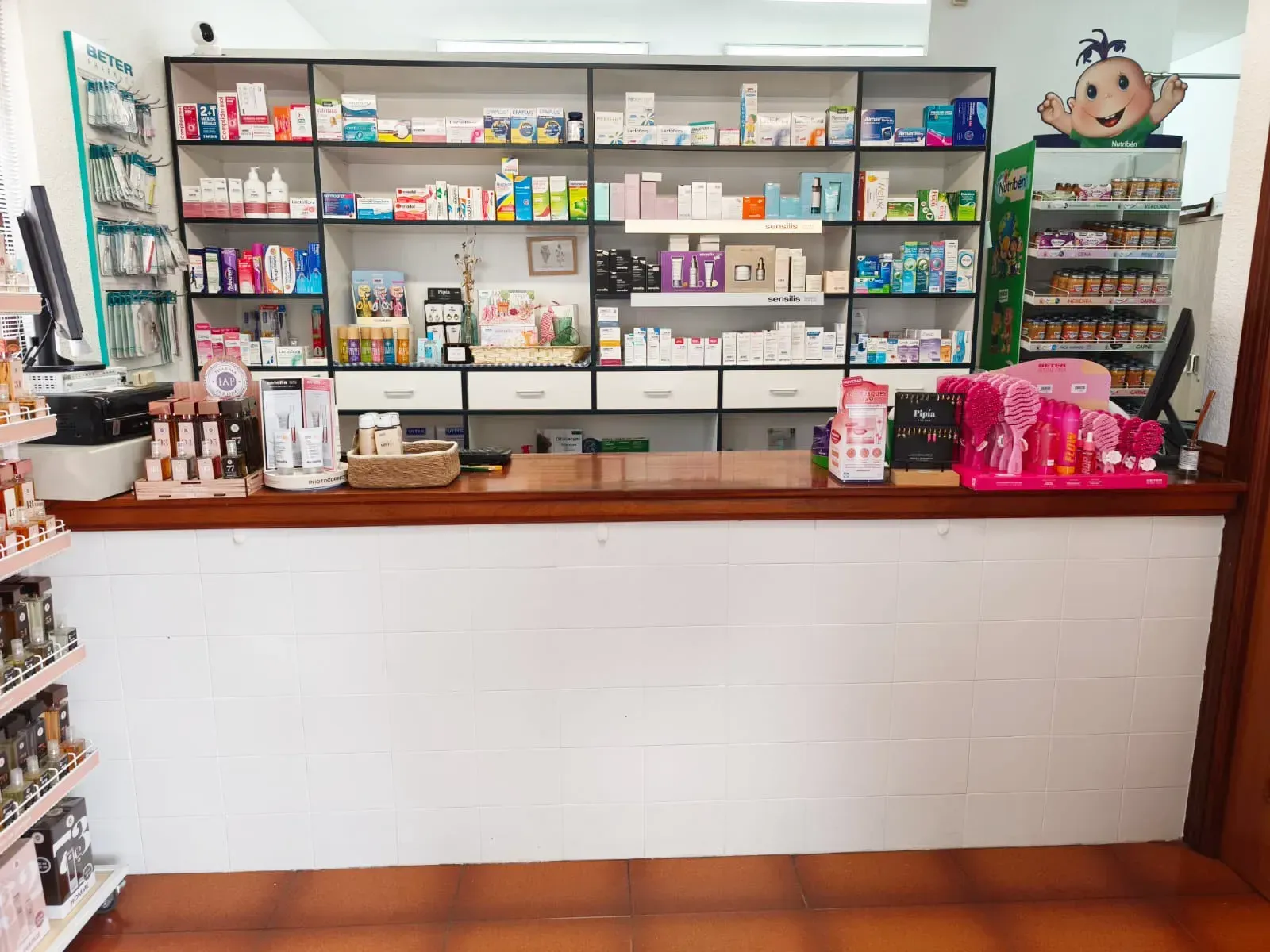 Mostrador de una pequeña tienda con estantes llenos de coloridos aperitivos, bebidas y artículos de tocador detrás.