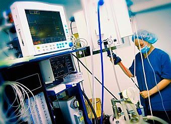 Un cirujano está de pie en una sala de operaciones con un monitor.