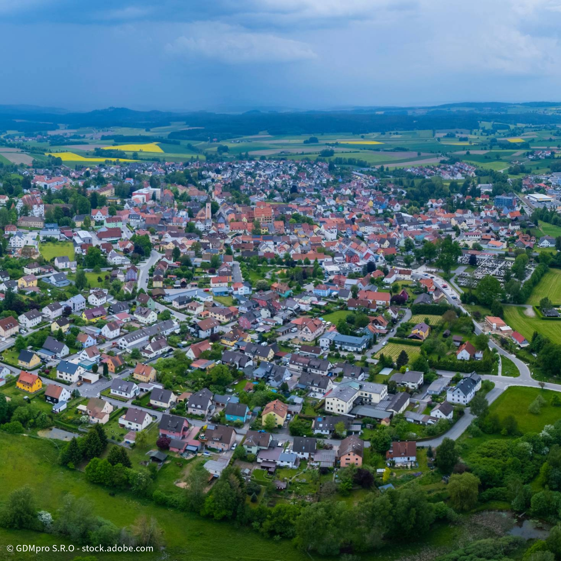 Luftaufnahme einer idyllischen Kleinstadt mit roten Dächern, umgeben von grüner Landschaft und Feldern in Deutschland