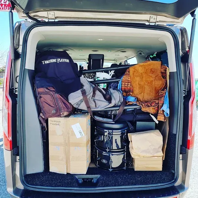 La parte trasera de una camioneta está llena de cajas y una batería.