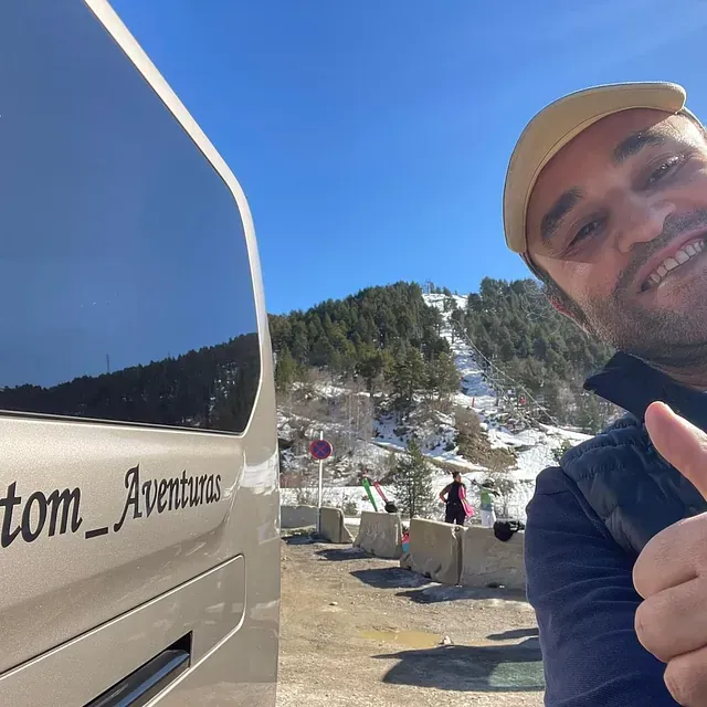 Un hombre levantando el pulgar frente a una camioneta que dice tom_aventuras