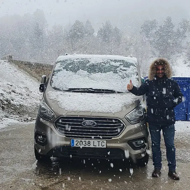 Un hombre haciendo un gesto de aprobación con el pulgar delante de una furgoneta Ford.