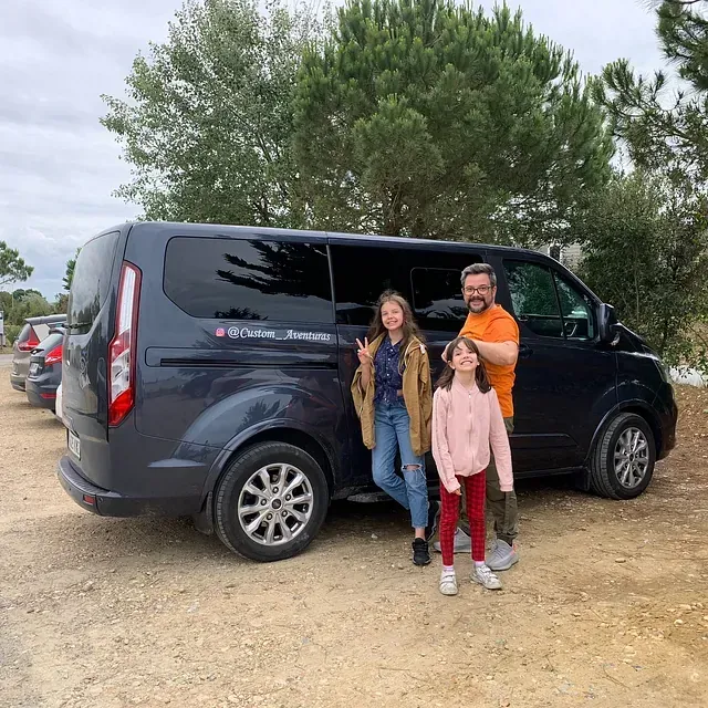 Una familia posa para una foto delante de una camioneta.
