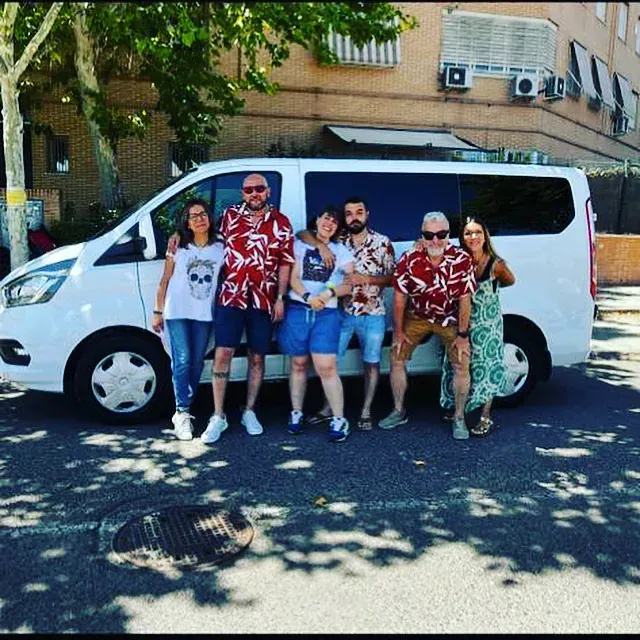 Un grupo de personas posando delante de una furgoneta blanca.