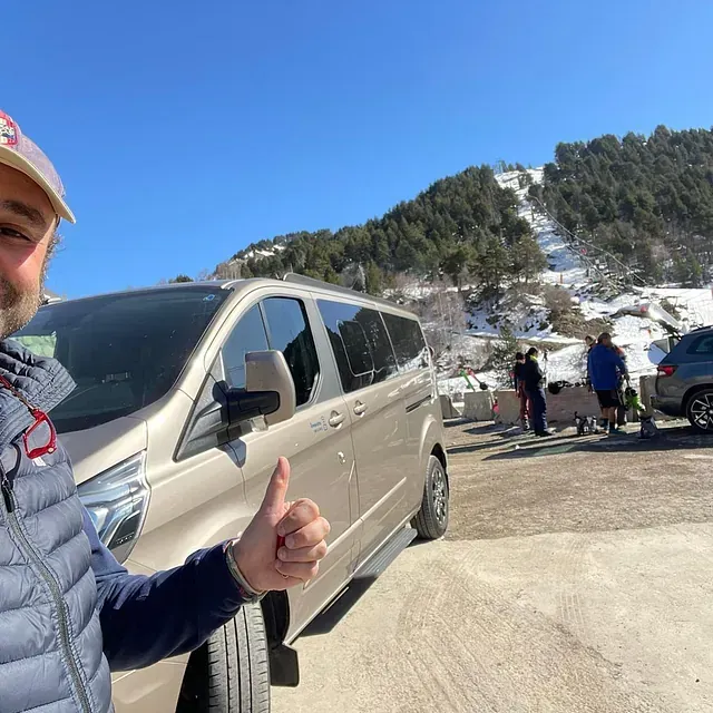 Un hombre está haciendo un gesto de aprobación con el pulgar delante de una furgoneta.