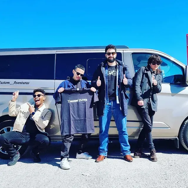 Un grupo de hombres posa frente a una camioneta que dice 'Falcon Avenue' en el costado.