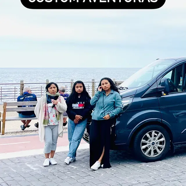 Tres mujeres están paradas frente a una camioneta azul.