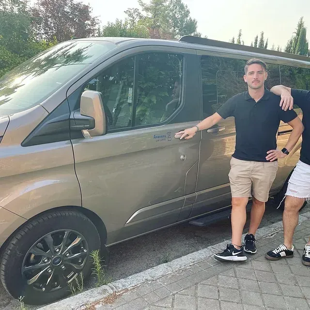 Dos hombres de pie junto a una camioneta que dice