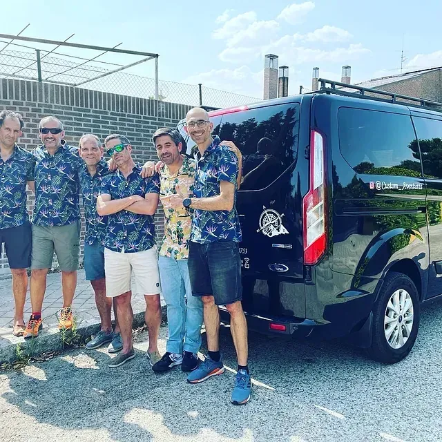 Un grupo de hombres posa para una fotografía frente a una camioneta negra.