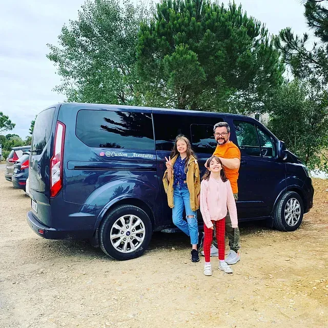 Un hombre y dos niños están parados frente a una camioneta azul.