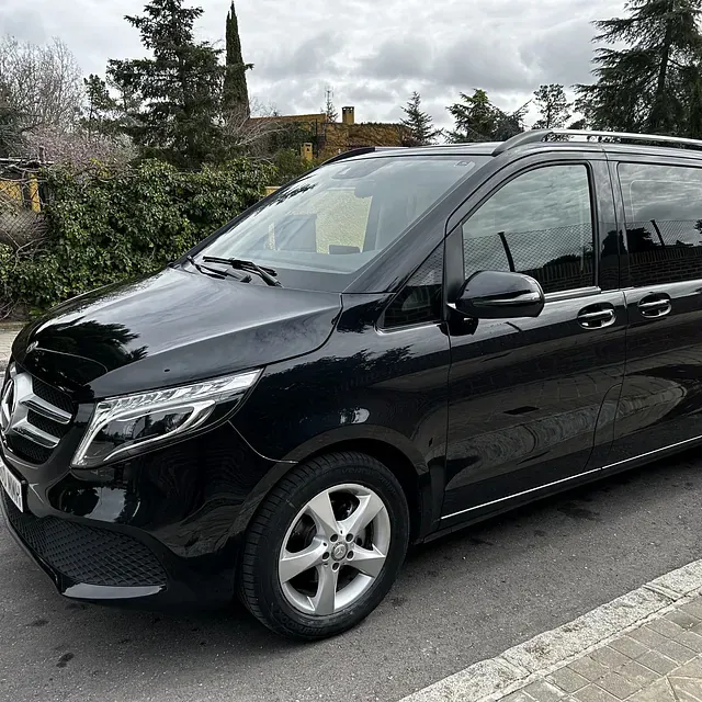 Una minivan negra está estacionada al costado de la carretera.