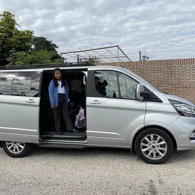 Una mujer está parada en la puerta de una camioneta plateada.