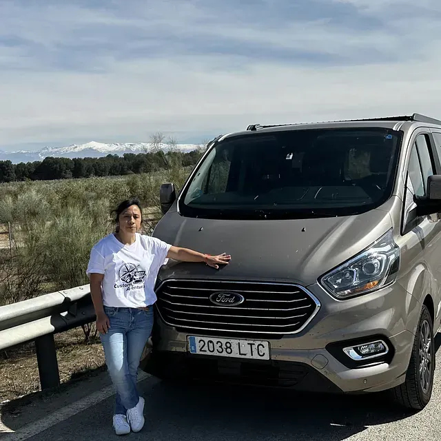 Una mujer está parada al lado de una camioneta Ford al costado de la carretera.