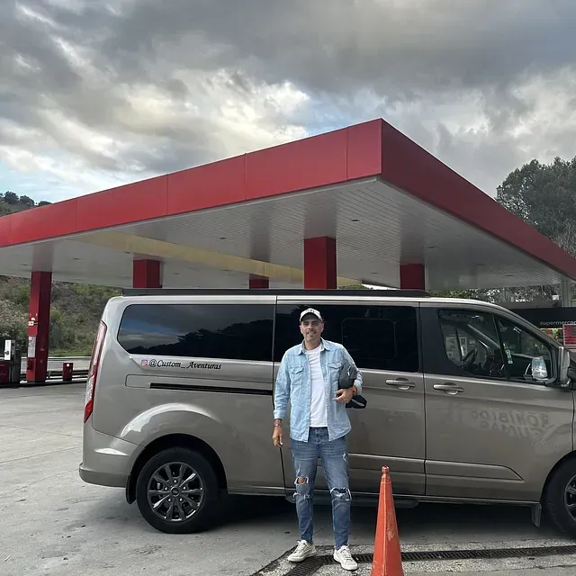 Un hombre parado junto a una camioneta en una gasolinera.