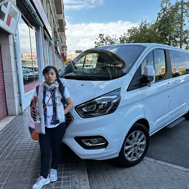 Una mujer está parada frente a una camioneta blanca.