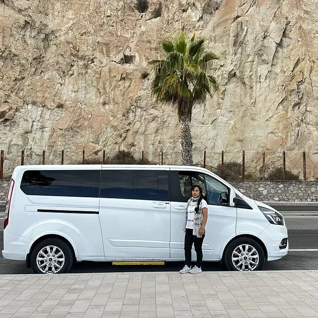 Una mujer está parada frente a una camioneta blanca.