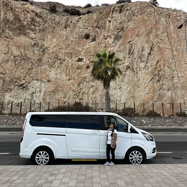 Una mujer está parada junto a una camioneta blanca al costado de la carretera.
