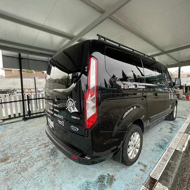 Una camioneta negra está estacionada bajo un toldo en un estacionamiento.