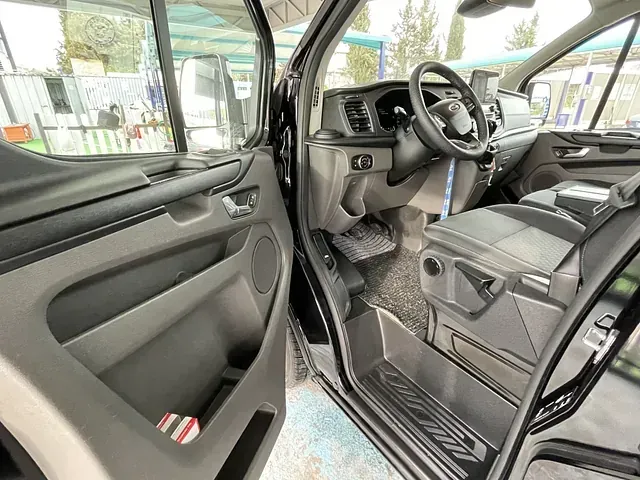 El interior de una camioneta negra con la puerta abierta y un volante.