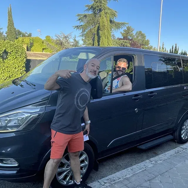 Dos hombres posan para una foto frente a una camioneta negra.