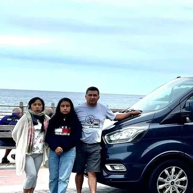 Un hombre y dos mujeres posan para una foto frente a una camioneta.