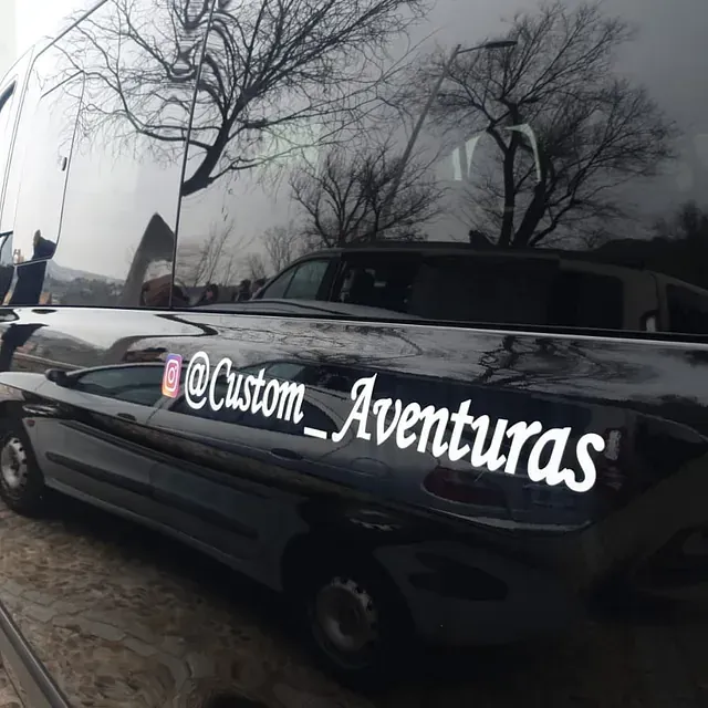 Un coche negro con una pegatina en el lateral que dice Custom Aventuras.