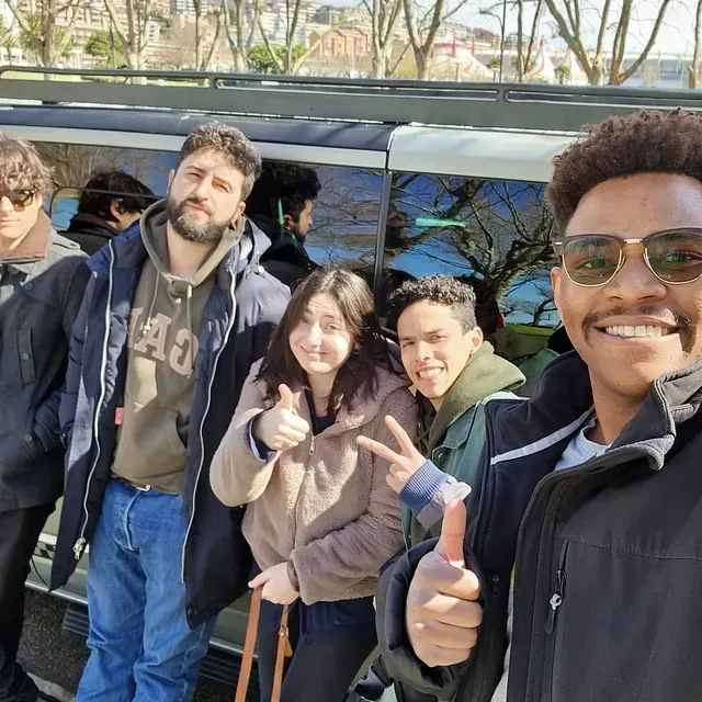 Un hombre que lleva gafas de sol está haciendo un gesto de aprobación con el pulgar hacia arriba a un grupo de personas.