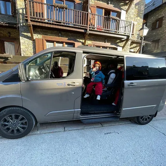Una familia está sentada en una camioneta con la puerta abierta.