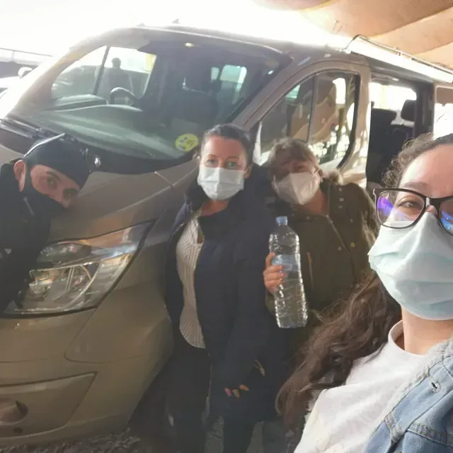 Un grupo de personas con mascarillas de pie frente a una camioneta.