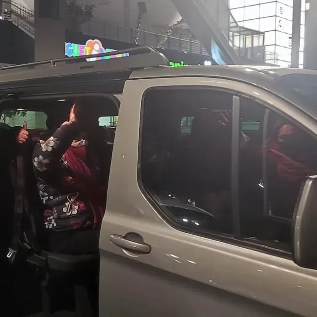 Una mujer hace un gesto de aprobación con el pulgar mientras está sentada en un coche.