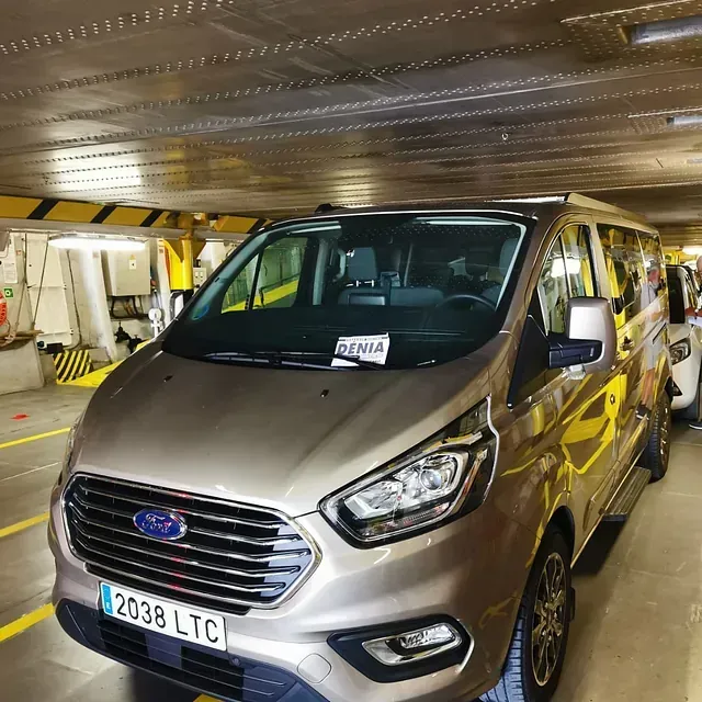 Una furgoneta Ford con matrícula 2038 ltc está estacionada en un estacionamiento.