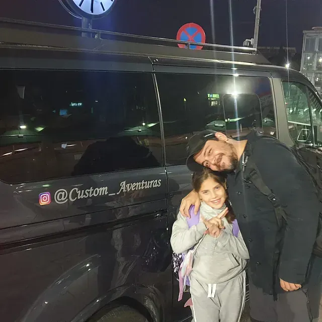 Un hombre y una niña están parados frente a una camioneta.