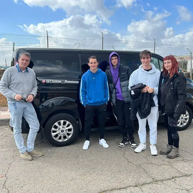 Un grupo de personas está de pie frente a una camioneta negra.