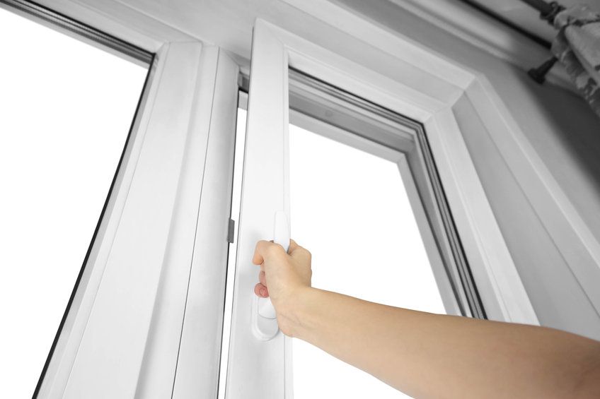 Una persona abre una ventana blanca con la mano.