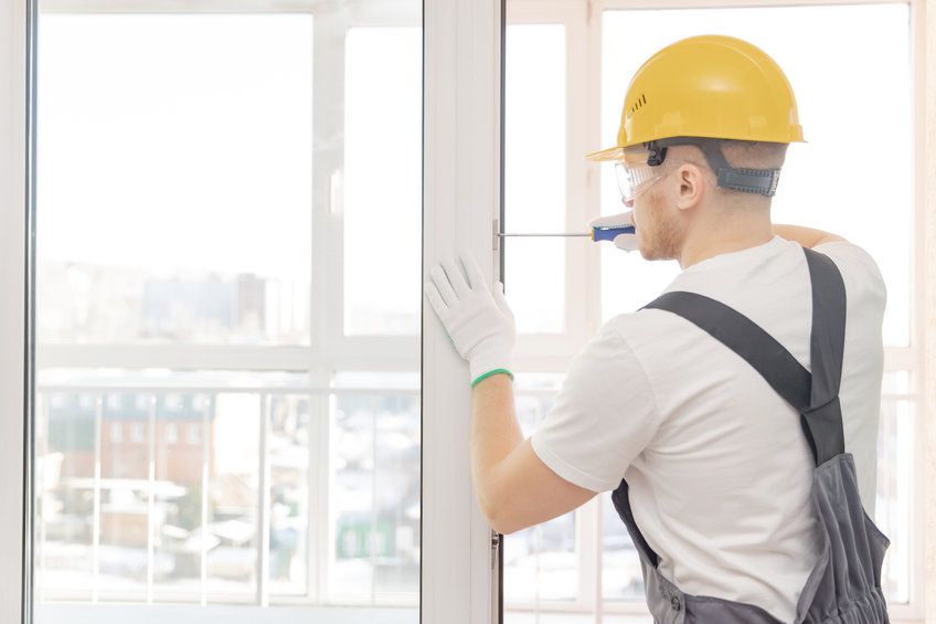 Un hombre está instalando una ventana en una casa.