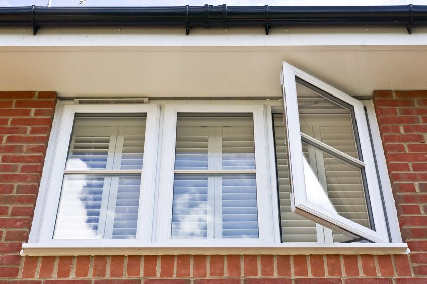 Una ventana blanca está abierta sobre un edificio de ladrillo.