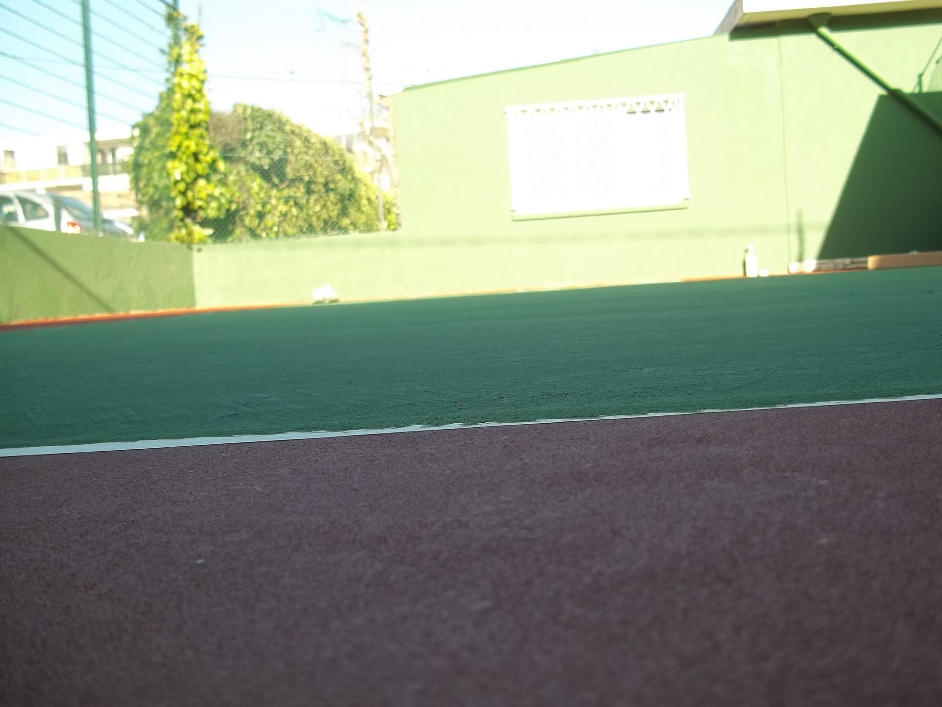 Gros plan sur un terrain de sport vert avec une bordure marron foncé et un mur vert en arrière-plan.