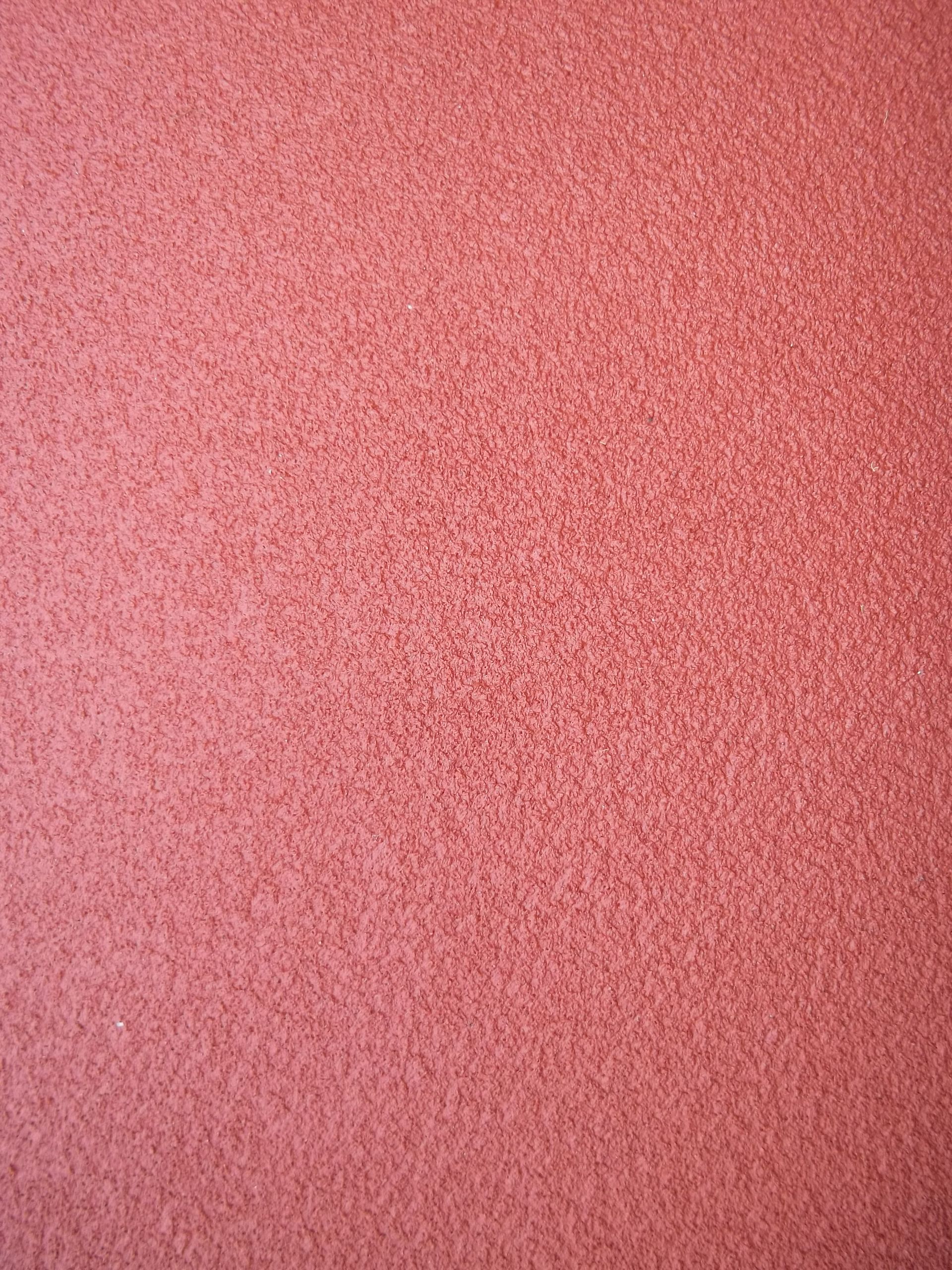 Surface rouge texturée, probablement une piste d'athlétisme.