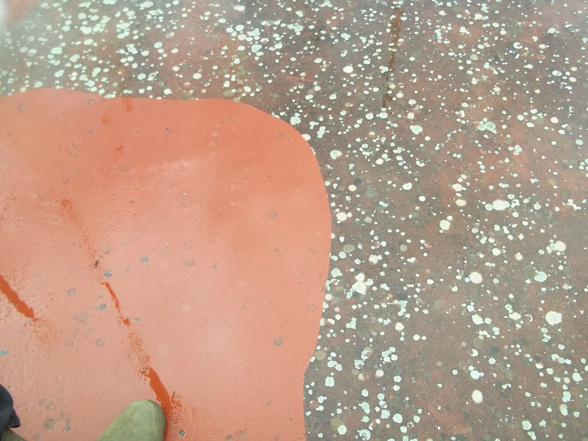 Surface peinte en rouge avec des éclaboussures, coin d'une autre surface visible.