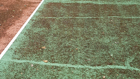 Gazon artificiel vert et marron avec des lignes et des fissures blanches.