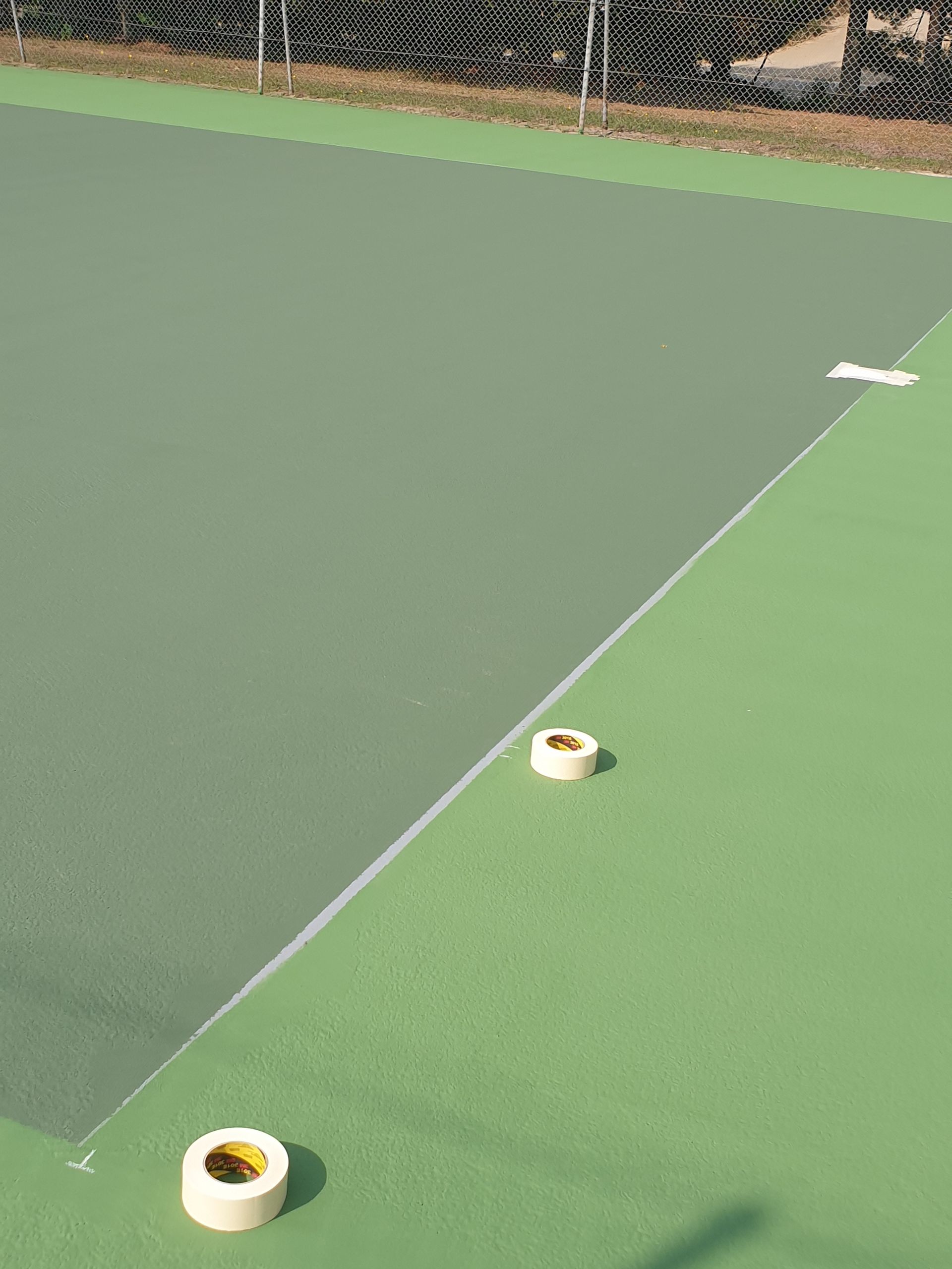 Court de tennis avec surfaces vertes et grises et marquages ​​au ruban adhésif blanc.