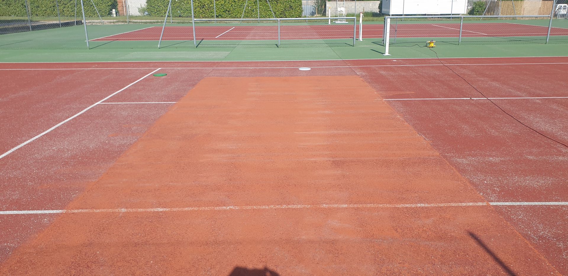 Court de tennis en terre battue, lignes et filet en arrière-plan.