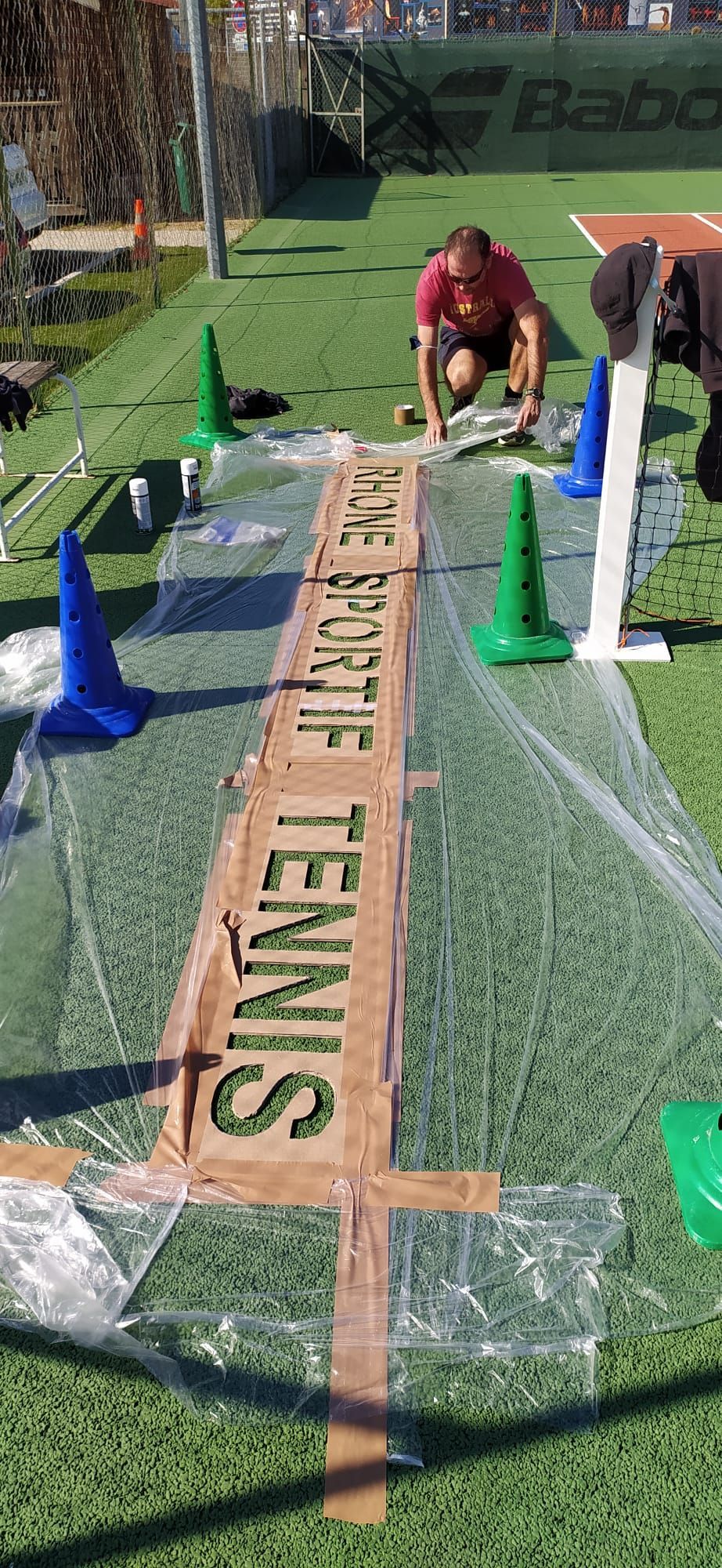 Réfection en gros plan d'un court de tennis. Pose du nom du court au sol.