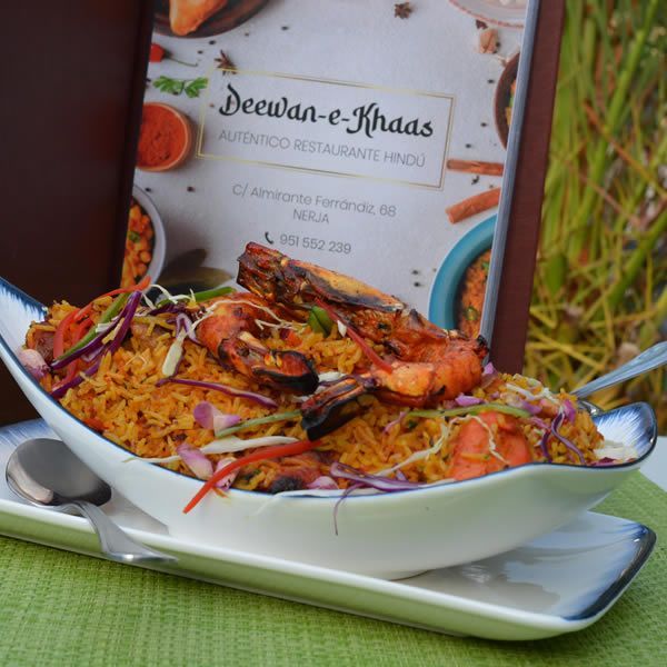 Pescado a la parrilla y arroz en una fuente blanca con el menú del restaurante detrás.