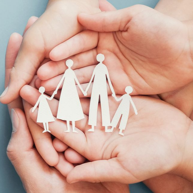 Des mains enserrent une silhouette en papier représentant une famille se tenant la main.