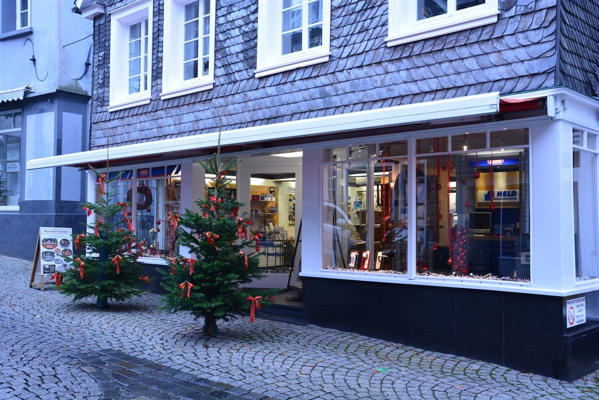 Eine Ladenfront mit Weihnachtsbäumen davor.