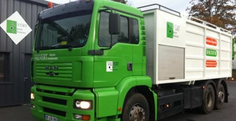 Camion MAN vert et blanc pour la collecte des déchets, stationné, logo sur le côté.